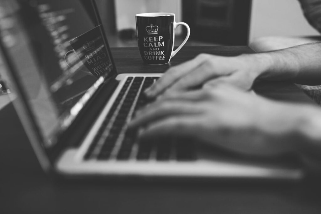 pexels-photo-160109 Monochrome image of hands on a laptop keyboard with a coffee mug, coding in progress.